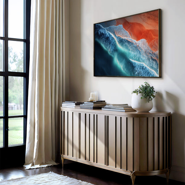 Ember Tide artwork in a dark thin frame above a slatted console with books and potted plant.