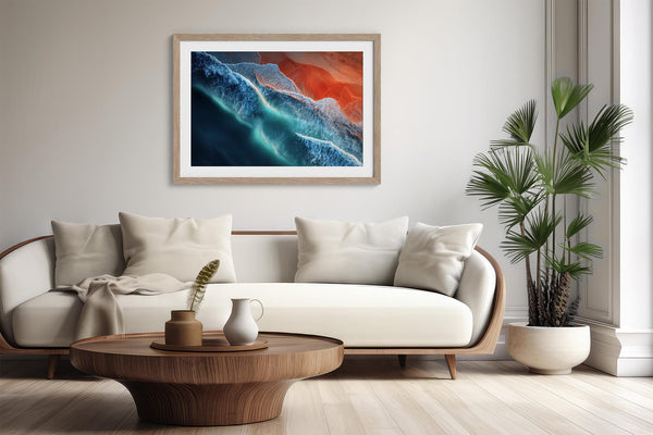 Ember Tide print in a light wood frame above a curved cream sofa and round coffee table.