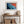 Ember Tide print in a light wood frame above a rustic console with woven baskets.