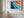 Close wall view of Ember Tide coastal artwork in a light wood frame with white matting.