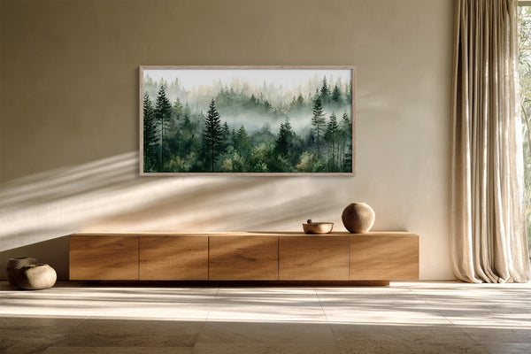 Framed misty pine forest watercolor hanging above a long wooden sideboard in sunlit space.