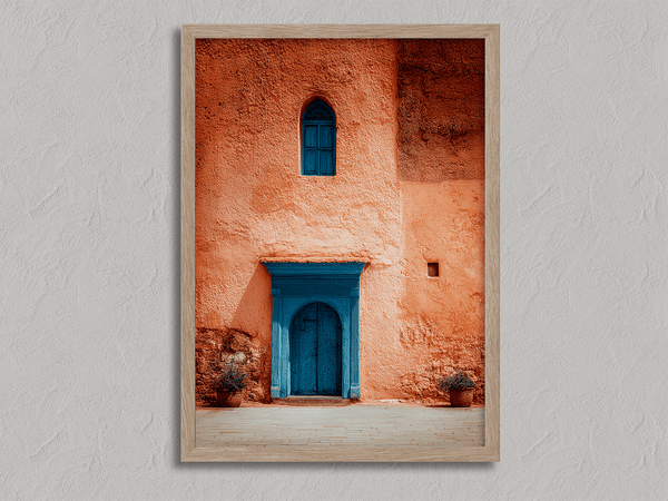 Framed Moroccan street scene art print featuring a vivid blue doorway and ochre wall. A soulful, timeless piece for eclectic interiors.