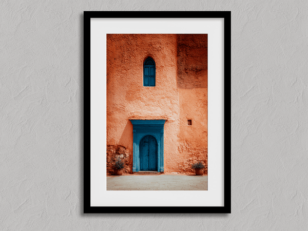 Framed Moroccan street scene art print featuring a vivid blue doorway and ochre wall. A soulful, timeless piece for eclectic interiors.
