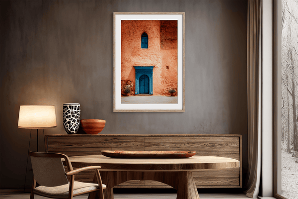 Framed Moroccan street scene art print featuring a vivid blue doorway and ochre wall. A soulful, timeless piece for eclectic interiors.