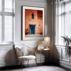 Framed Moroccan street scene art print featuring a vivid blue doorway and ochre wall. A soulful, timeless piece for eclectic interiors.