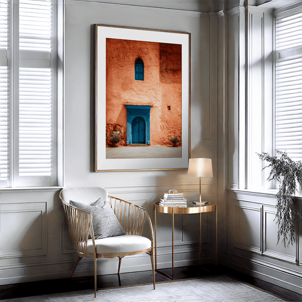 Framed Moroccan street scene art print featuring a vivid blue doorway and ochre wall. A soulful, timeless piece for eclectic interiors.