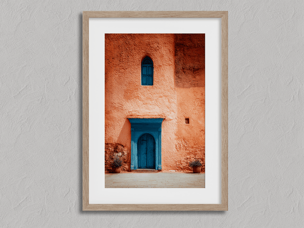 Framed Moroccan street scene art print featuring a vivid blue doorway and ochre wall. A soulful, timeless piece for eclectic interiors.