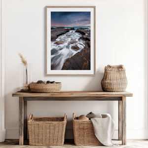 Framed wall art of the Australian coast with rugged rocks, azure sea, and moody skies. A striking coastal landscape print. Ready to hang.