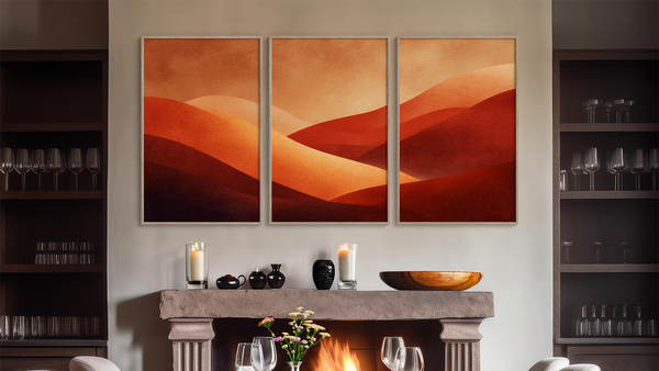 Three abstract landscape paintings of desert sand dunes above a fireplace in a room with shelves. www.AtelierLumin.art. 