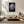 Framed black-and-white rain-covered leaf artwork above a low cream sectional and wooden coffee table.