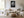 Framed monochrome wet leaf artwork above a white sofa, wood coffee table, and round ottoman.