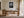 Framed monochrome leaf photograph above a wooden desk with a chair and table lamp.