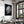 Large black-framed wet leaf photograph above a set dining table beside tall windows.