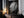 Large black-framed raindrop-covered leaf artwork leaning on a dark wooden cabinet with candles.