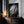 Large black-framed raindrop-covered leaf artwork leaning on a dark wooden cabinet with candles.