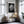 Gold-trimmed framed wet leaf photograph above a gold chair and small round side table.