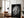 Large black-framed wet leaf artwork leaning against a wall beside an armchair and floor lamp.