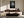 Framed black-and-white rain-covered leaf photograph above a dark wood sideboard and curved sofa.