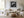 Black-framed lighthouse artwork above a white sofa, low wood table, and round woven ottoman.