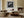 Black-framed lighthouse wall art above a sectional sofa beside a lit built-in fireplace.