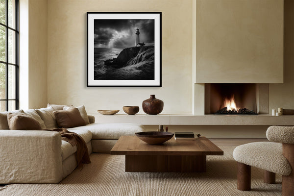 Black-framed lighthouse wall art above a sectional sofa beside a lit built-in fireplace.