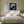 Black-framed lighthouse print centered above a neatly made bed with light wood nightstands.