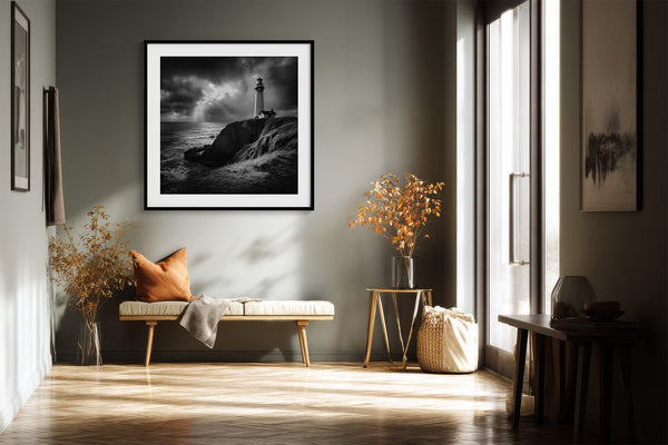 Black-framed lighthouse print above a bench with an orange pillow in a sunlit hallway.