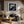 Black-framed lighthouse wall art above a dark sofa and wooden coffee table beneath exposed beams.