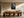 Framed black-and-white leaf vein photograph above a long wooden dining table and sculptural chairs.