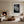Light-framed black-and-white leaf wall art above a fireplace in a neutral living room.