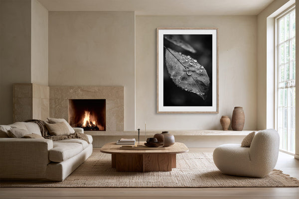 Light-framed black-and-white leaf wall art above a fireplace in a neutral living room.