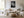 Light-framed black-and-white leaf wall art above a cream sofa, coffee table, and woven ottoman.