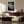Light-framed dew-covered leaf wall art above a curved sofa and dark wooden sideboard.