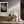 Light-framed dew-covered leaf wall art above a wooden console with vases and dried branches.
