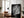Large unframed black-and-white leaf print leaning beside a leather armchair and floor lamp.