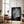 Large unframed black-and-white leaf print leaning beside a leather armchair and floor lamp.