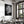 Black-framed monochrome leaf artwork displayed above a set dining table near a large window.