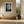 White-matted leaf print in a light wood frame above a built-in bench.
