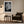 White-matted leaf print in a light wood frame above an armchair and side table.