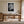 White-matted black-and-white leaf print in a light wood frame above a wooden desk.