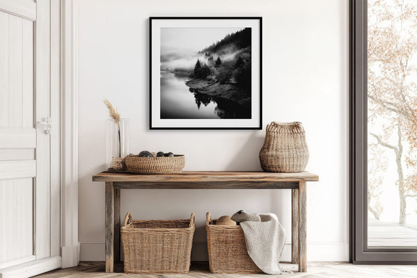 Black-framed Mistwater Valley river print above a rustic console with woven baskets.