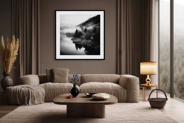 Black-framed misty river print above a curved beige sofa and round coffee table.