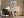Framed abstract artwork above a dark upholstered armchair beside a floor lamp and small table.