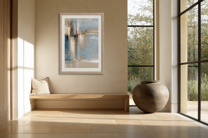 Framed blue and beige abstract artwork above a built-in bench beside large black-framed windows.