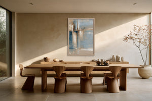 Framed abstract artwork above a long wooden dining table surrounded by sculptural wooden chairs.