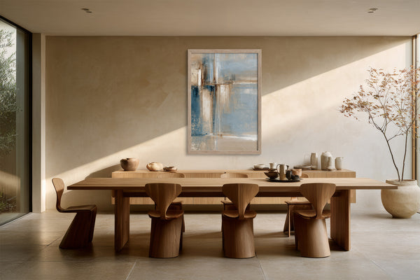 Framed abstract artwork above a long wooden dining table surrounded by sculptural wooden chairs.