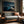 Blue-toned desert dune artwork in a slim wood frame above a gray sofa.