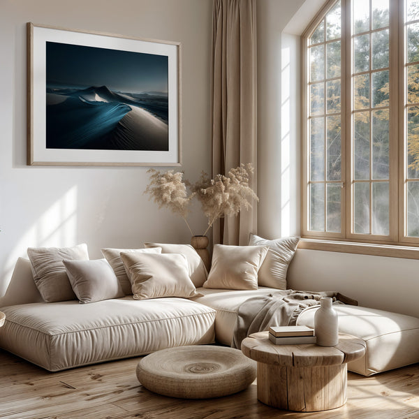 Desert dune print with white mat and light wood frame above a cushioned seating area.