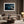 Matted desert dune artwork in a light wood frame above a beige sofa and round coffee table.