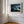 Close view of matted desert dune artwork in a light wood frame on a white paneled wall.